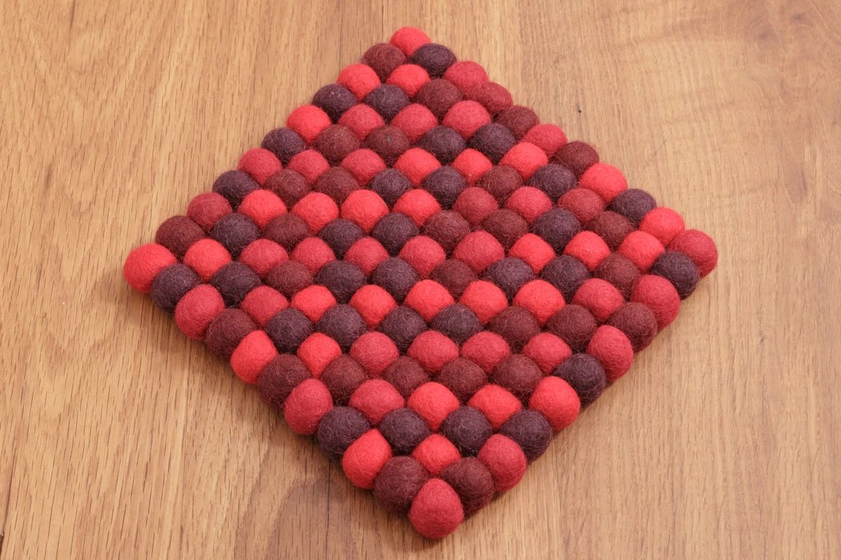 Quadratischer Untersetzer aus 2 cm Filzkugeln in Rottönen