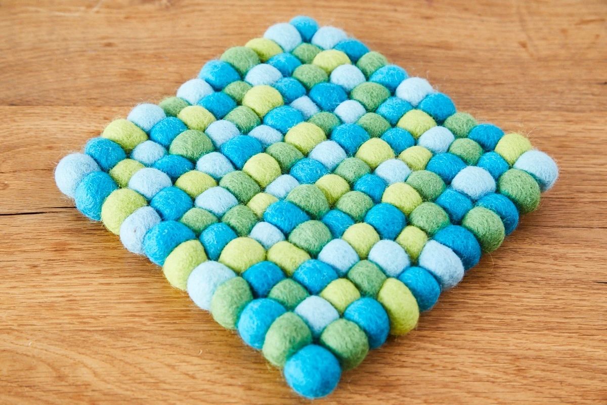 Quadratischer Untersetzer aus 2 cm Filzkugeln in Hellblau-Gelb-Tönen