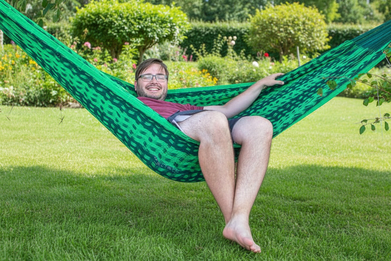 Mexikanische Hängematte Mikko aus hellgrün-dunkelgrünem robusten Baumwollnetz im Garten mit einer Person