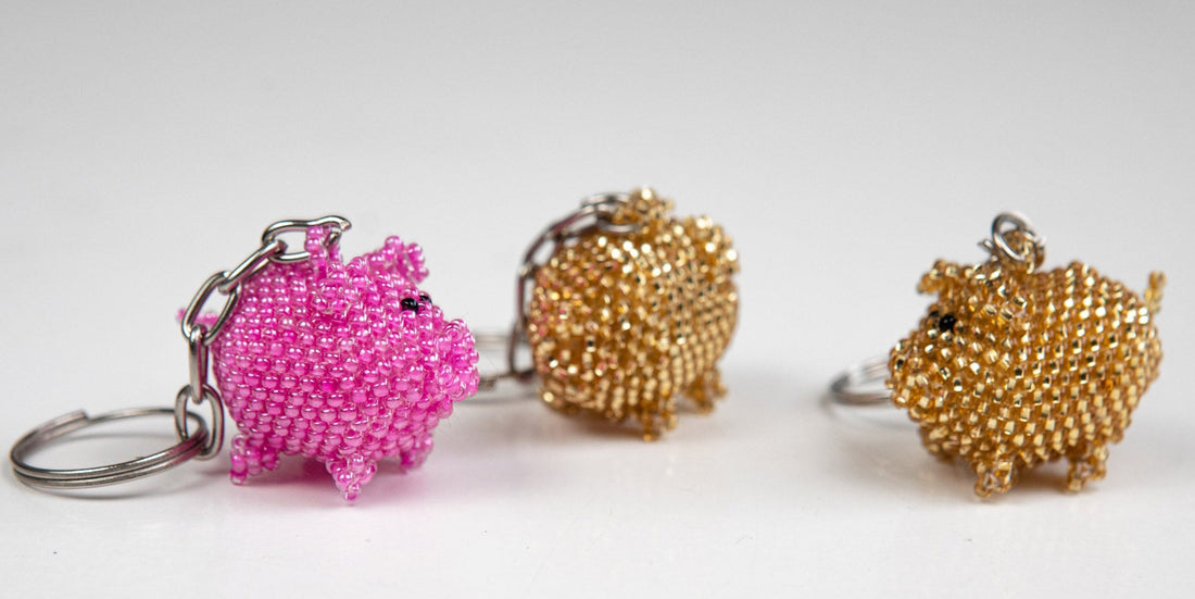Schlüsselanhänger aus Glasperlen als Glücksschweinchen in rosa und goldfarben