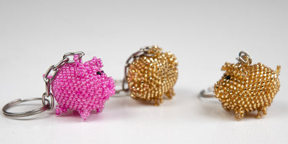 Schlüsselanhänger aus Glasperlen als Glücksschweinchen in rosa und goldfarben