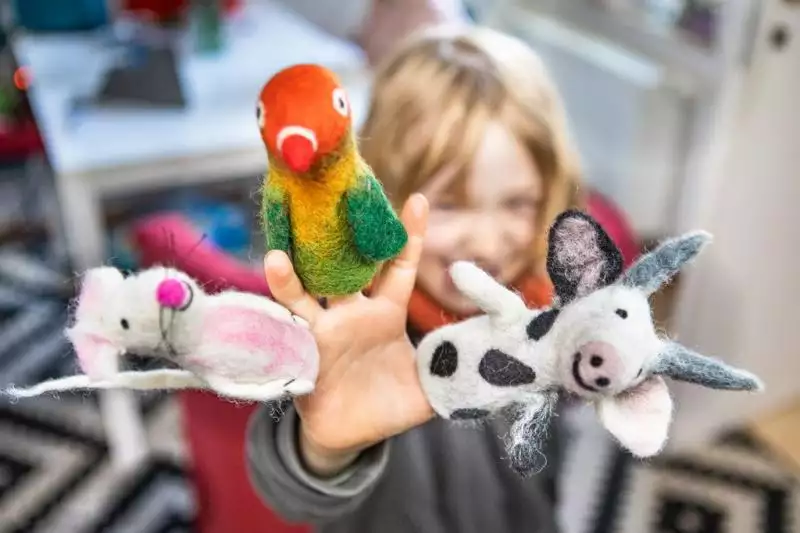 Kind mit Fingerpüppchen Maus, Papagei, Kuh